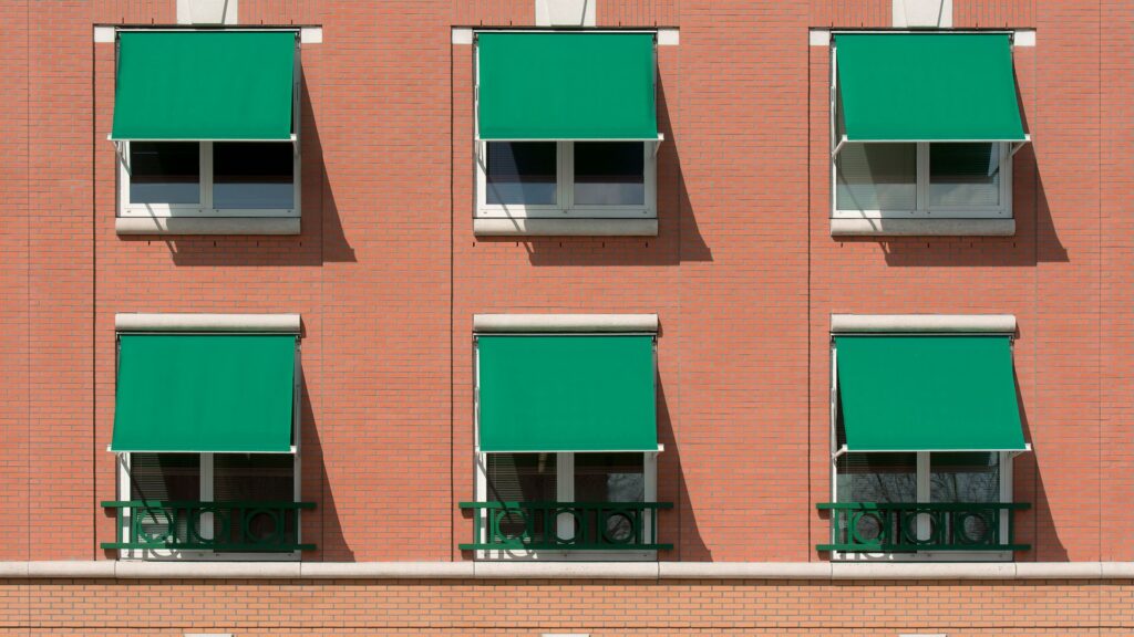 Tende da sole contro il caldo sulle finestre di un edificio residenziale in mattoni