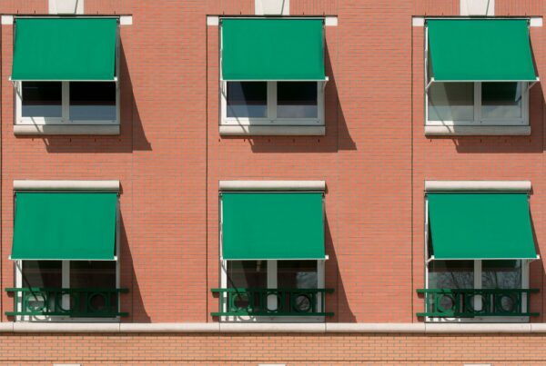 Tende da sole contro il caldo sulle finestre di un edificio residenziale in mattoni