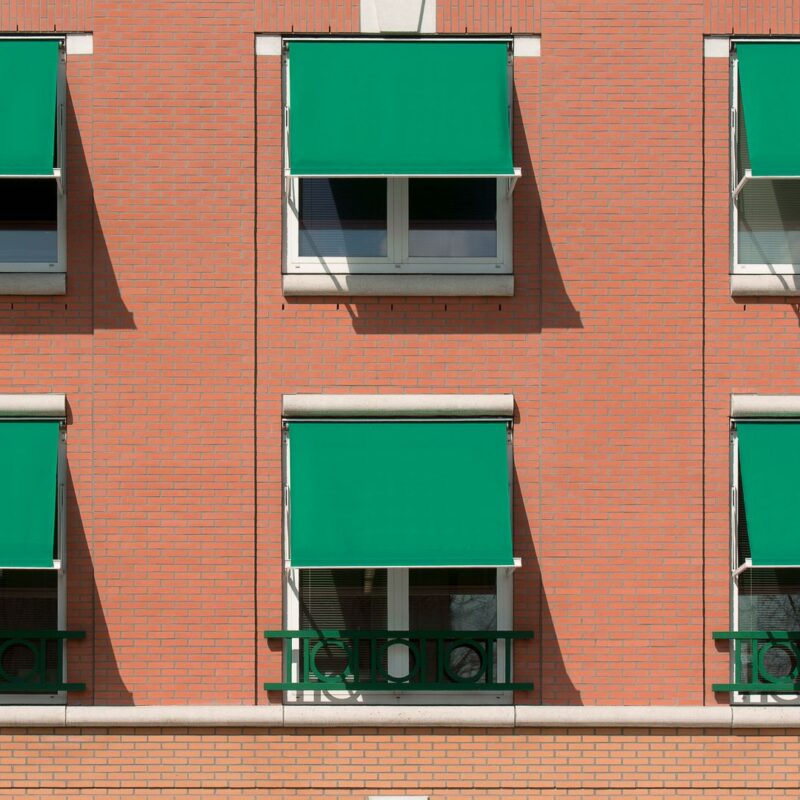 Tende da sole contro il caldo sulle finestre di un edificio residenziale in mattoni