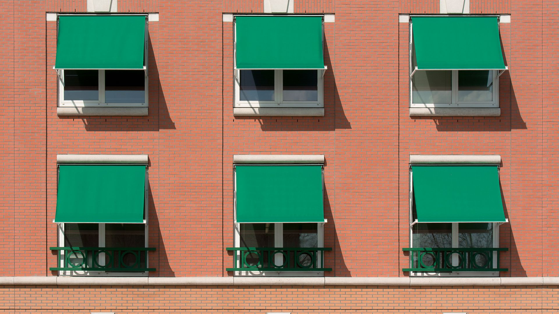 Tende da sole contro il caldo sulle finestre di un edificio residenziale in mattoni